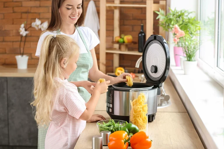 Frau und Tochter kochen mit einem Multikocher in der Küche