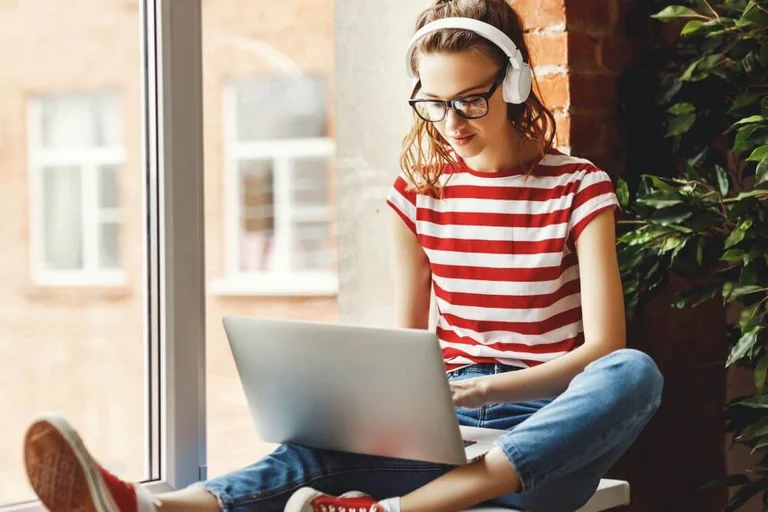 Eine Frau arbeitet an ihrem Laptop mit Bluetooth Kopfhörern