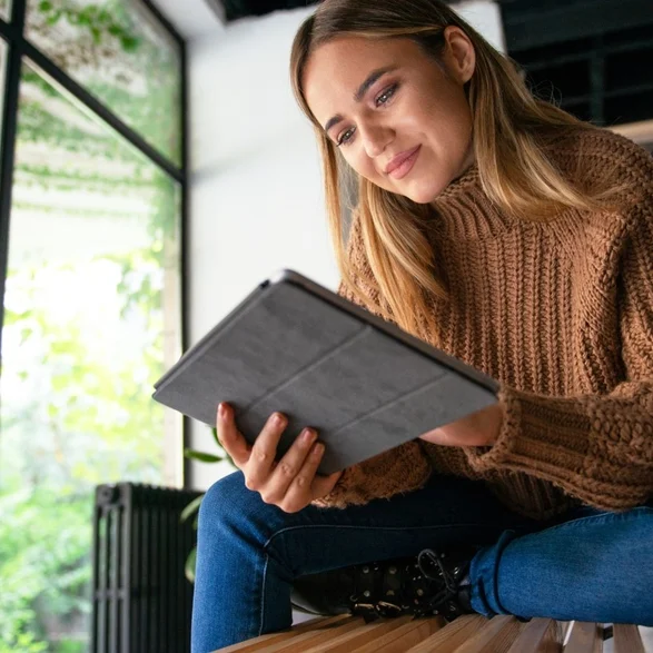 Eine glückliche Frau mit einem Apple Tablet vor einer Fensterfront