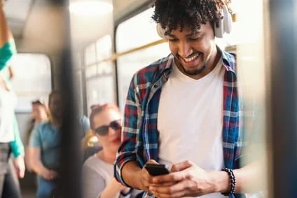 Mann im Bus hört mit Noise-Cancelling-Kopfhörern Musik