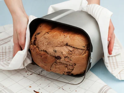 Jemand holt ein frisches Brot aus einer Brotbackmaschine