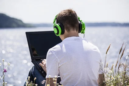 Junge am Meer spielt mit Gaming Laptop