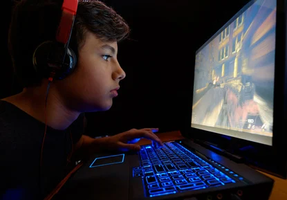 Junge spielt im Dunkeln mit Gaming-Laptop