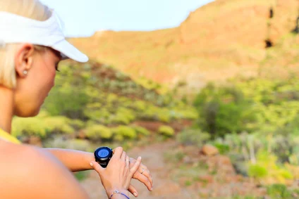 Frau beim Joggen mit GPS-Uhr im Park