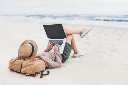 Junger Mann liegt mit 13 Zoll Laptop am Strand