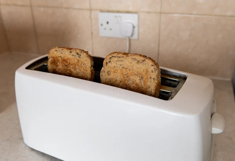 Weißer Langschlitztoaster in einer Küche, der gerade Körnertoastbrot getoastet hat