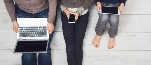 Eine Familie nutzt Laptop, Smartphone und Tablet